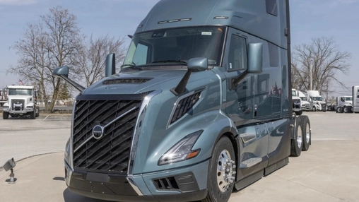 Front view of a grey Volvo semi-truck in a commercial vehicle yard with other trucks in the background