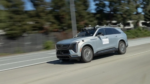 A self-driving test vehicle with roof-mounted sensors and research labelling travelling on a multi-lane road
