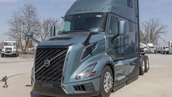 Front view of a grey Volvo semi-truck in a commercial vehicle yard with other trucks in the background